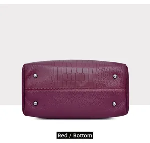 Detailed bottom view of burgundy bucket bag featuring crocodile texture and protective metal studs