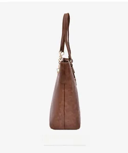 Side view of brown textured leather tote bag featuring gold hardware and long shoulder strap