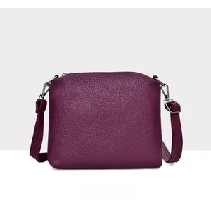 Detail view of the purple pebbled leather shoulder bag with silver metal hooks and zipper