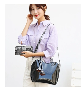Fashionable black patent leather tote bag with snakeskin print wallet on a female model