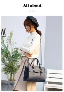Detail of navy blue crocodile pattern leather handbag with handles and shoulder strap