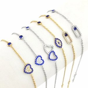 Detalle de pulseras de corazón con piedras de circón azul y blanco en acabados oro y plata