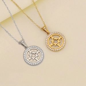 Dettaglio di ciondoli a stella tondi in oro e argento con zirconi bianchi intarsiati