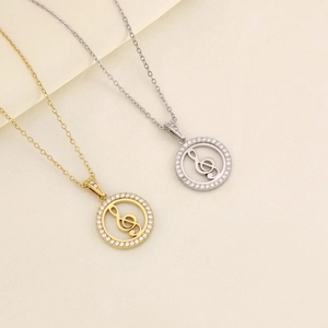 Dettaglio delle collane con pendente chiave di violino in oro e argento con cristalli pavé