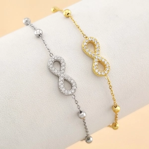 Close-up of infinity symbol bracelets in gold and silver with cubic zirconia inlays