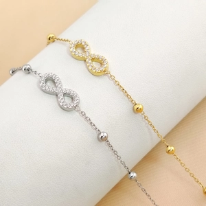 Macro view of gold and silver infinity symbol bracelets with small round beads on chains
