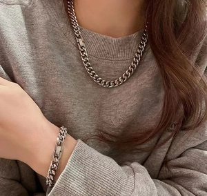 Détail du collier et bracelet gourmette en acier inoxydable argenté sur un mannequin