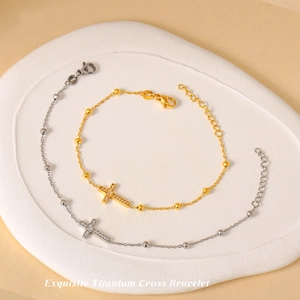 Bracelets croix en titane or et argent avec zircons sur un plateau d'exposition blanc