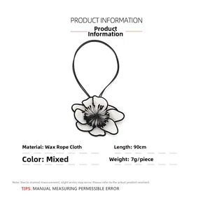 Detail view of handmade white fabric flower pendant with long black wax cord and floral core