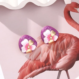 Détail macro de boucles d'oreilles fleur en émail avec texture marbre violet et perle