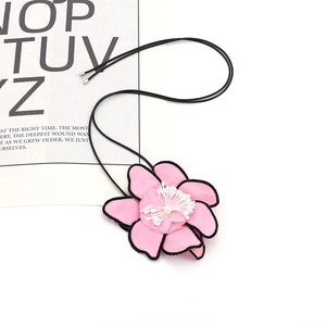 Detail of pink fabric flower pendant with black cord and elegant white stamens