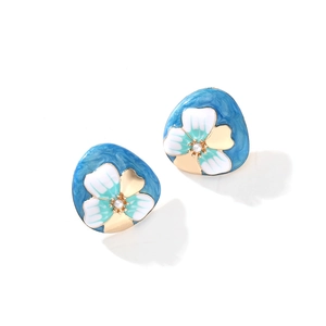 Gros plan sur les boucles d'oreilles fleur en émail avec texture bleu sable