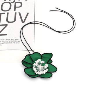 Detailed macro view of dark green fabric flower petals with white stamens on a black choker