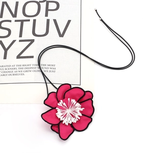 Detailed macro shot of a magenta fabric flower pendant with a black cord necklace