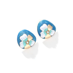 Détail de boucles d'oreilles fleurs en émail avec perle sur base bleue nacrée