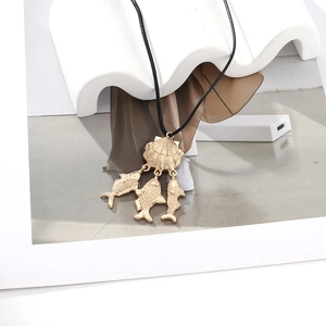 Golden seashell and tropical fish pendant necklace with black cord on white stand