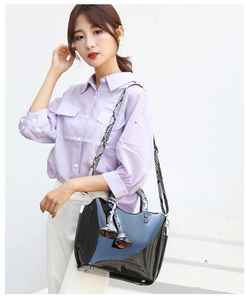Detail of black patent leather handbag with stylish snake print wide shoulder strap