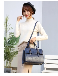 Detail of navy blue crocodile pattern texture on a stylish tote bag with gold hardware