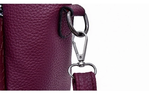 Close-up of dark purple lychee grain leather bag with gunmetal buckle and neat stitching