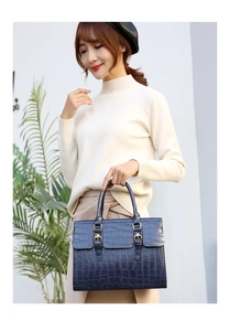 Detailed shot of dark blue crocodile texture handbag with gold buckles and flap design