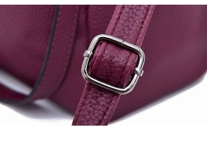Close-up of wine red lychee textured leather strap with silver metal adjustment buckle