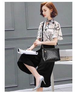 Detail of a chic black textured shoulder bag with gold chain and floral fashion outfit