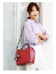 Detail of red patent leather tote with snake print strap and metal protective feet
