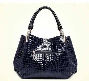 Glossy crocodile pattern handbag with woven handles and silver metal zipper on white background