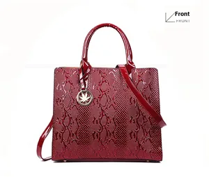 Front view of burgundy snake-pattern faux leather handbag with leaf pendant detail