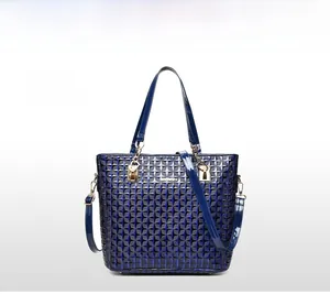 Close-up of dark blue patent leather tote bag with geometric star pattern and gold chain