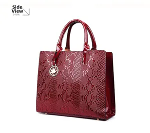 Detail of dark burgundy snakeskin embossed tote bag with metal maple leaf pendant