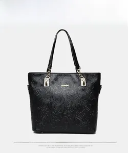 Detailed view of floral embossed black leather handbag with gold metal hardware