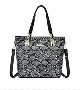 Detailed front view of snakeskin pattern tote bag with gold hardware and black handles