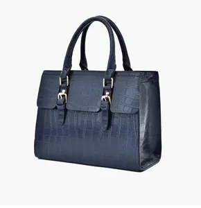 Detail view of deep blue faux crocodile texture handbag with gold buckles and dual handles