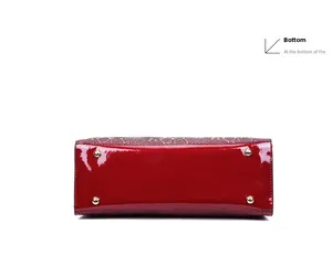 Detailed bottom view of red patent leather handbag with gold-tone protective metal feet