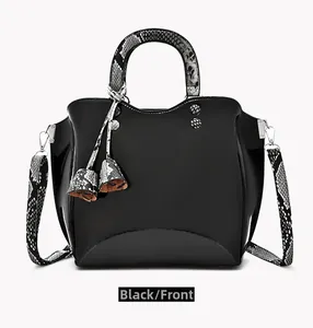 Close-up of black patent leather handbag with snake pattern handles and double tassels