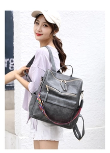 Dettaglio zaino retrò grigio scuro con tasche multiple e tracolla etnica intrecciata a colori