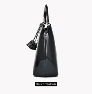 Side view of black patent leather handbag with smooth texture and silver metallic hardware