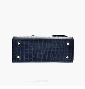 Detail view of the handbag bottom featuring gold feet and crocodile embossed texture