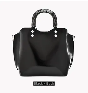 Detail showing the back view of a black glossy handbag with silver metal studs and snake-pattern handles