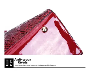 Close-up of golden protective studs on glossy wine red snakeskin texture handbag base