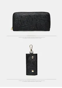 Close-up of black camellia embossed leather wallet and key pouch showing texture