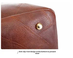 Detail van de bruine kunstlederen tasbodem met gouden beschermende noppen en stiksels