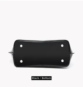 Detailed bottom view of black patent leather handbag with silver protective metal feet