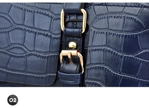 Close-up of dark blue crocodile texture leather with gold hardware and detailed stitching
