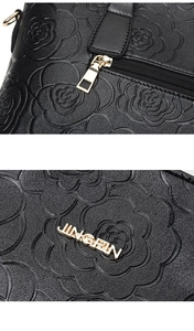 Macro view of floral embossed lychee pattern and gold metal branding on the black handbag