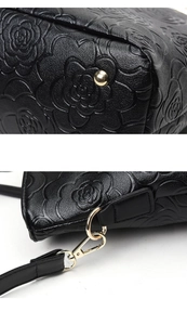 Detailed macro view of embossed camellia leather pattern and gold hardware on black handbag