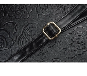 Detailed macro view of black litchi grain leather bag with camellia flower embossing