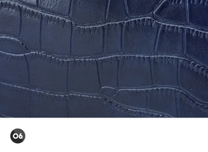 Close-up of blue crocodile embossed leather texture with precise stitching detail