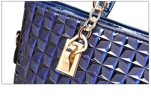 Detail of dark blue handbag featuring geometric diamond texture and gold metal hardware